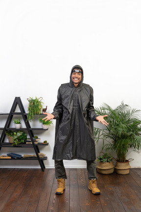 Smiling man in raincoat shrugging and spreading his arms